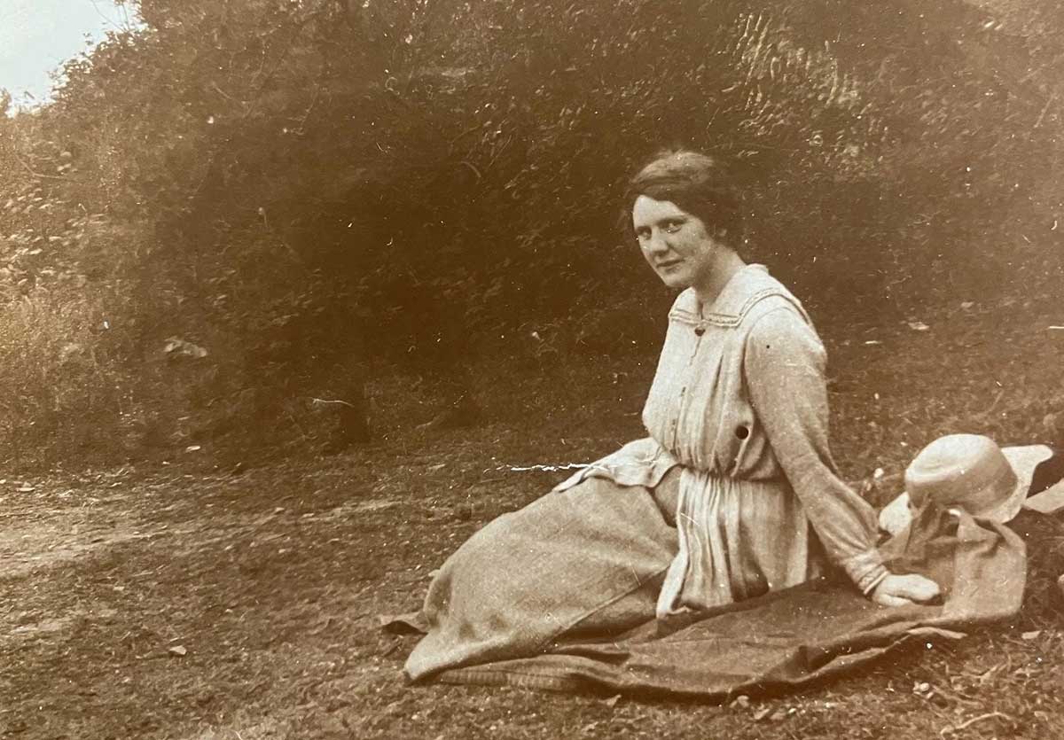 Writer, hill-walker, adventurer and explorer Nan Shepherd sits on the grass with nature in the background