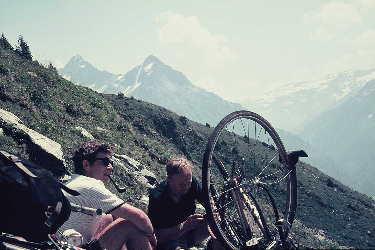 A couple of Rough Stuff Fellowship members taking a break in the mountains on a cycling trip with their bikes on a sunny day.