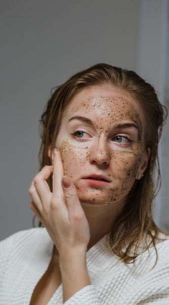 Blonde girl applying organic herbal mask on face