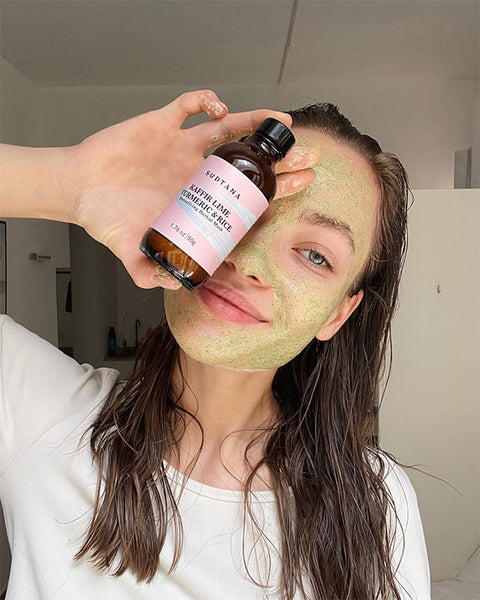 Influencer holding SUDTANA's Kaffir Lime Turmeric and Rice Herbal Mask applied to her face