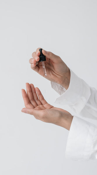 Woman dropping face oil on palm