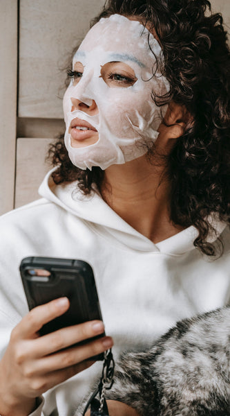 Woman using sheet mask while browsing on phone