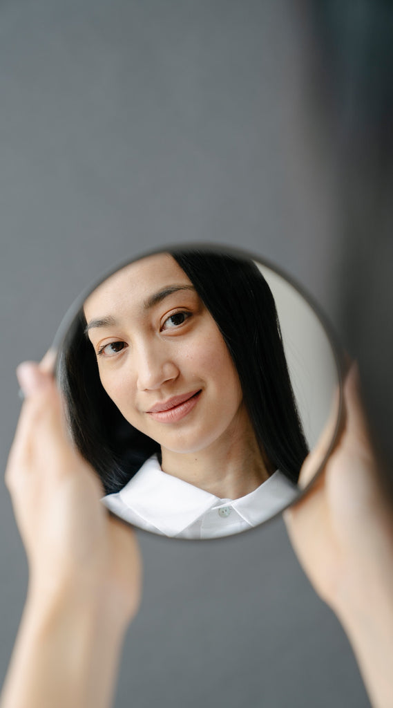 Woman with long straight black hair looking at mirror