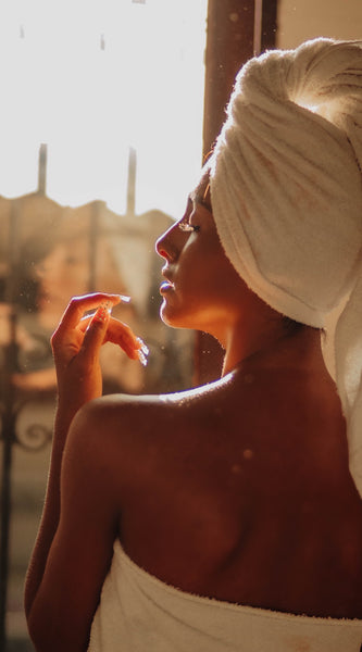 Woman with soft, smooth and hydrated skin in front of window after shower