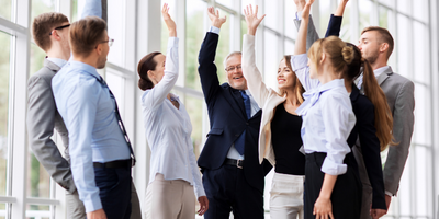 coworkers celebrating win in office setting with hands up excited 