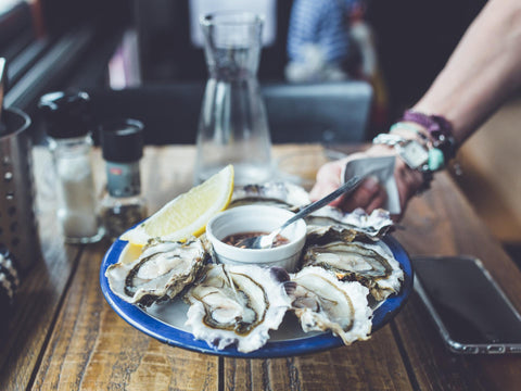 plate of oysters shucked open at a restaurant with lemon and sauce waiting to be consumed 