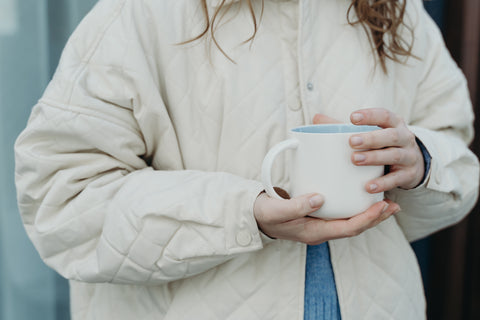 woman in winter jacket holding coffee mug