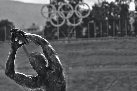 black and white olympic logo with bronze discus statue 