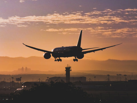 airplane flying through sky during sunset 