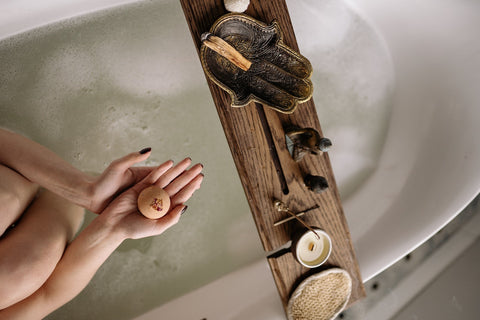 eco friendly bath bomb in hands above bathtub