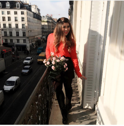 Jennifer Chan standing on a balcony next to pink flowers.