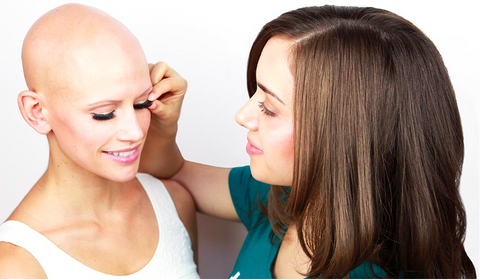 Woman putting on eyelash strips on another woman.