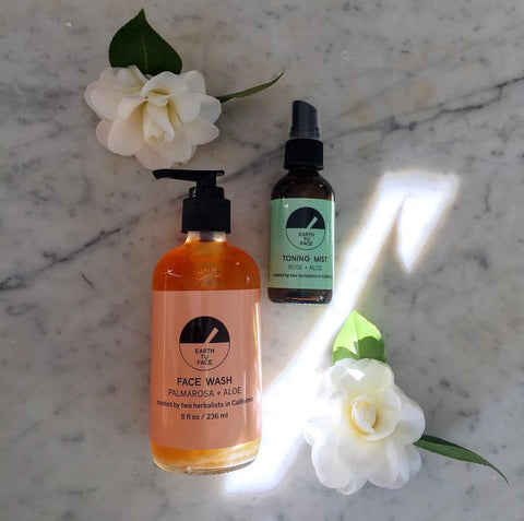 Skincare products lying on table with white flowers.