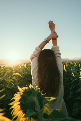 Woman stretching in field of sunflowers.
