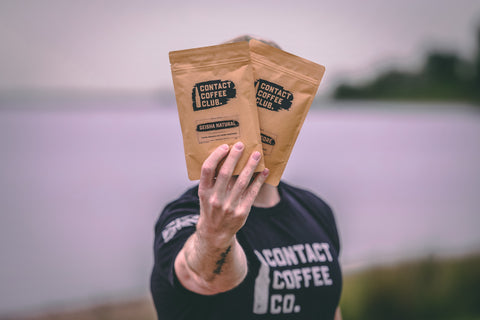 coffee subscription bags being held on a beach