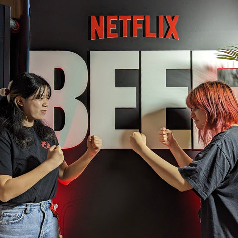 Two young women posing with fists in front of Netflix's BEEF banner