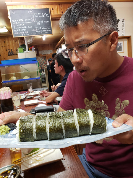 A man astonished a very large sushi roll