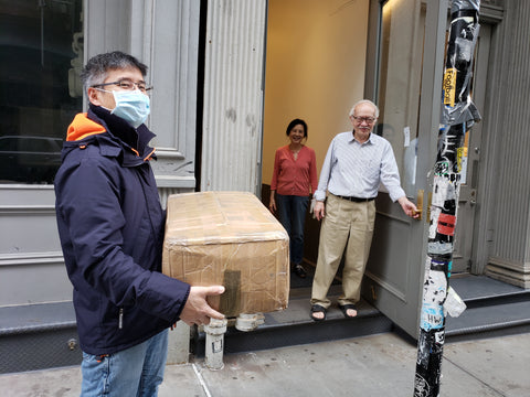 Man wearing mask holding mask and elderly parents in background