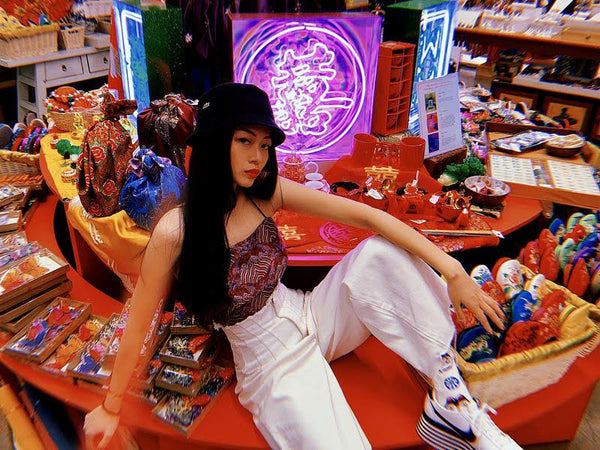 Artist Juno Shen posing in front of one of her neon light mahjong tile sculptures