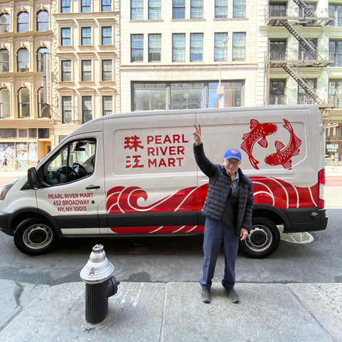 Pearl River Mart founder Mr. Chen throwing peace sign in front of newly designed PRM van