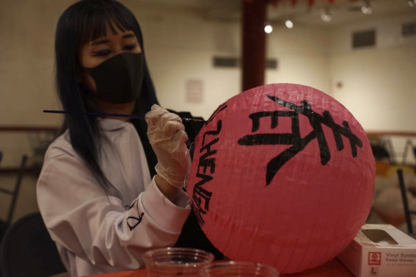 Volunteer paints a dedication on a lantern.