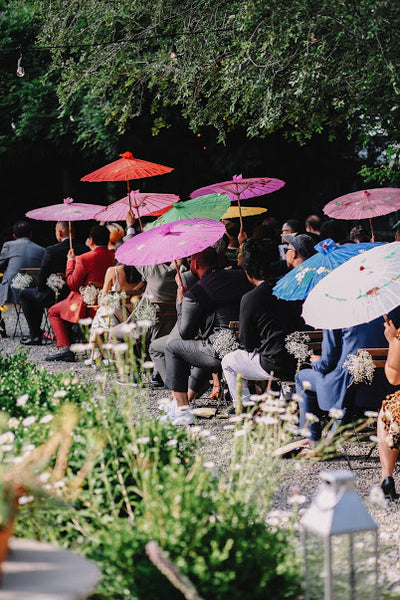 Guests at an outdoor wedding with colorful parasols