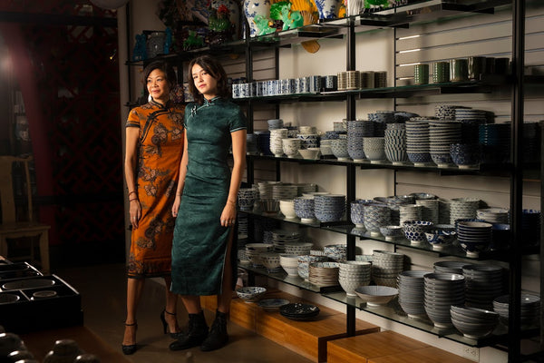 Christine Wong and Tien Lardner in qipaos in front of ceramic bowls