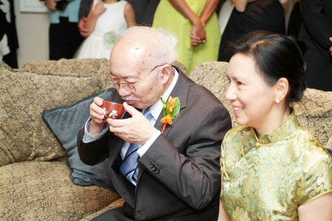 Mr. Chen drinks tea while Mrs. Chen smiles during the tea ceremony