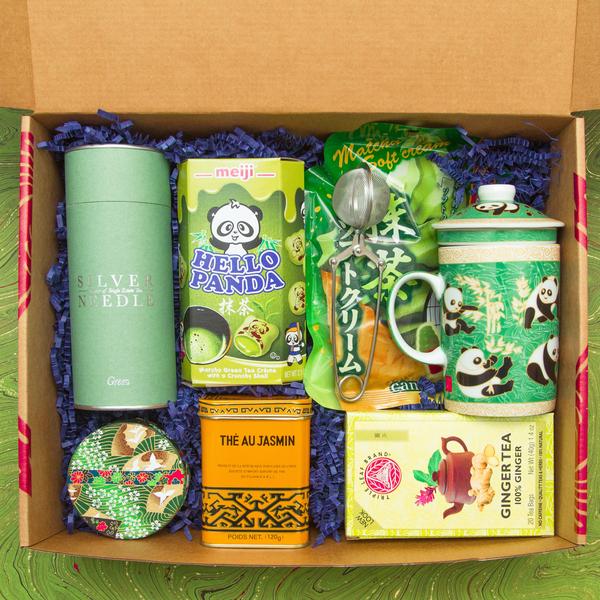 Box full of beautiful tea items, including artisnal jasmine green tea, a tea consister, jasmine tea in a tin, matcha Hello Panda cookies, green panda mug, and more