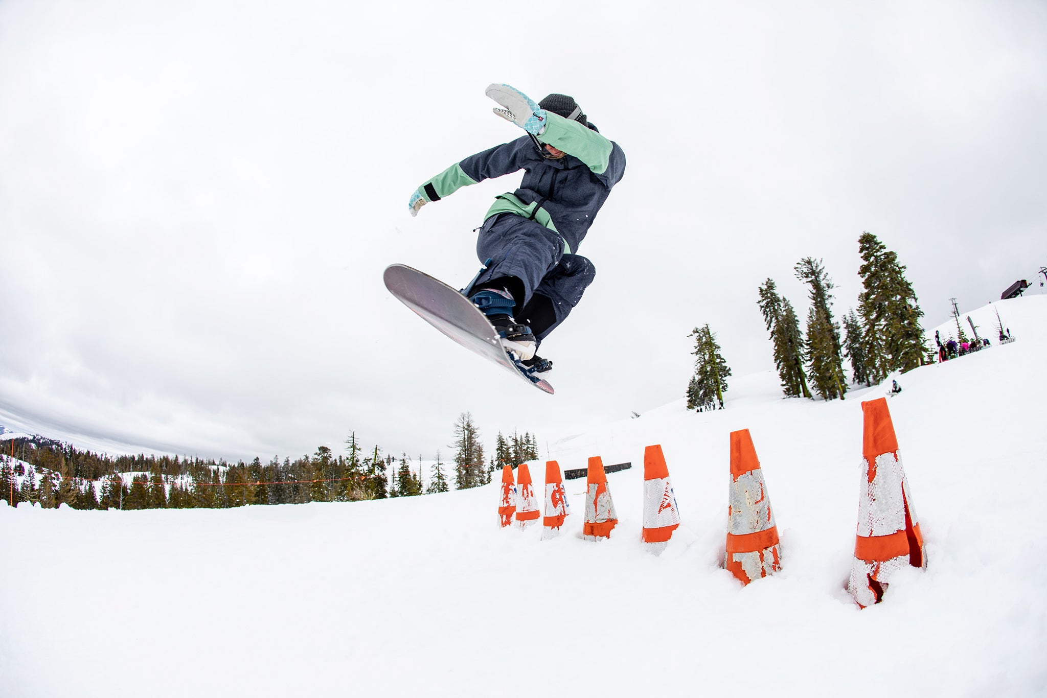 Snowboarder jumping over cones in snow