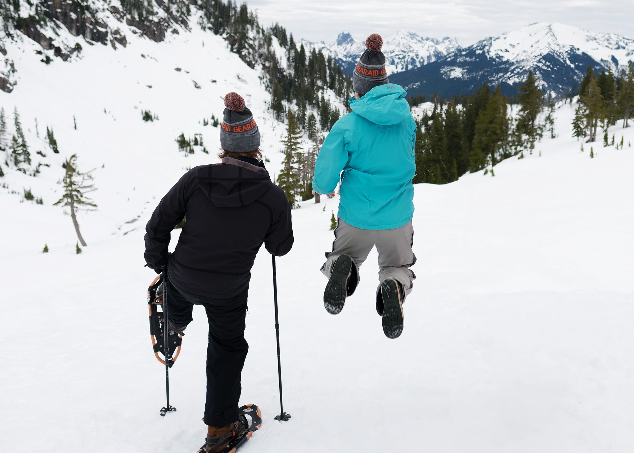 Snowshoer and hiker jumping in air on winter hike