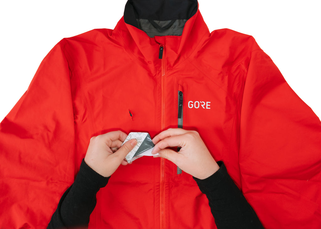 GEAR AID GORE TEX patch backing being removed to place on tear on GORE WEAR red jacket