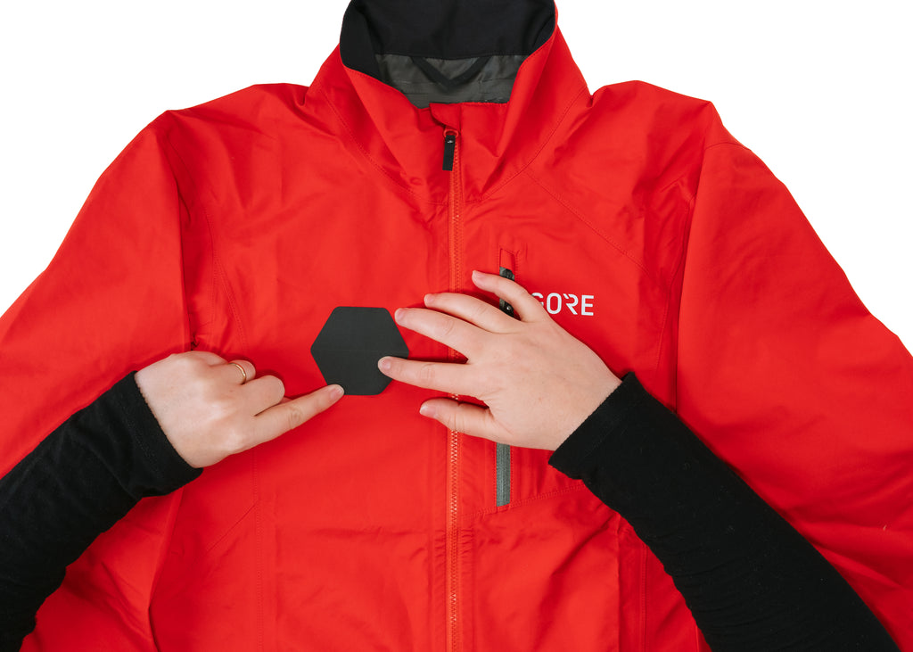GEAR AID Tenacious Tape GORE TEX patch applied to red jacket and being pressed on to remove bubbles