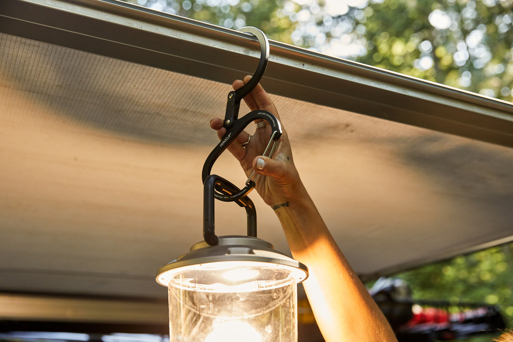 GEAR AID Heroclip holding an outdoor lantern, clipped to an awning on a truck camper set up