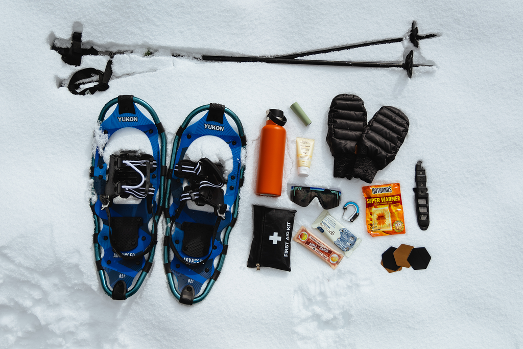 Snowshoes, poles, Hydroflask, Pit Viper Sunglasses, hand warmers, mittens, and more laid out snow