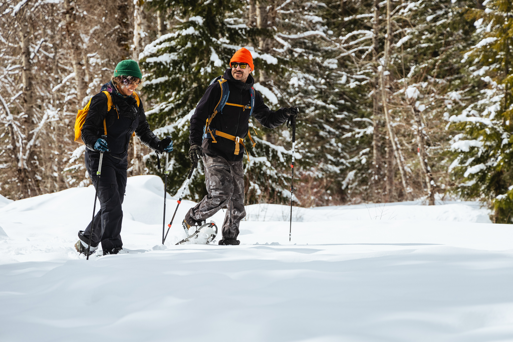 Two snowshoers bundled up and hiking in a winter landscape