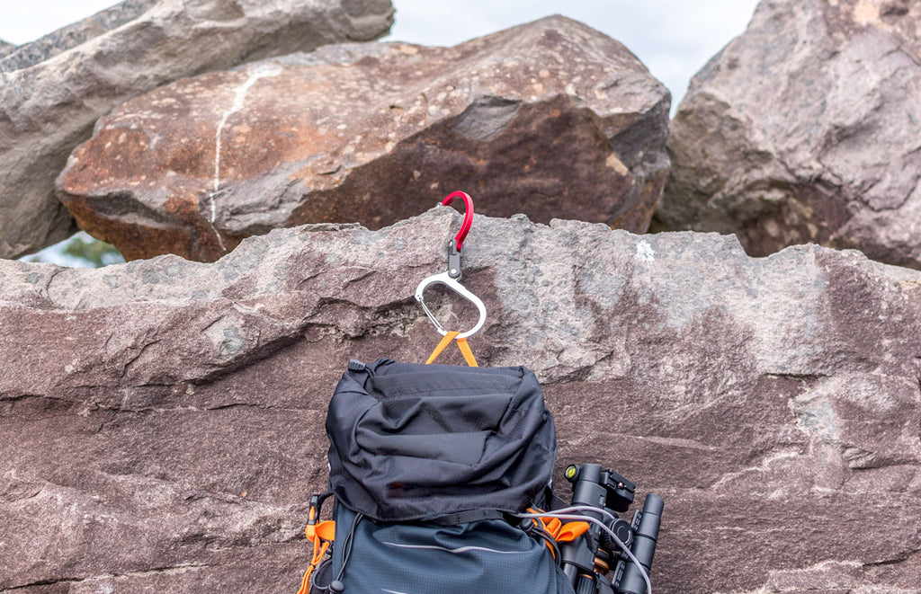 GEAR AID Heroclip hanging off a red rock with a black backpack attached to it