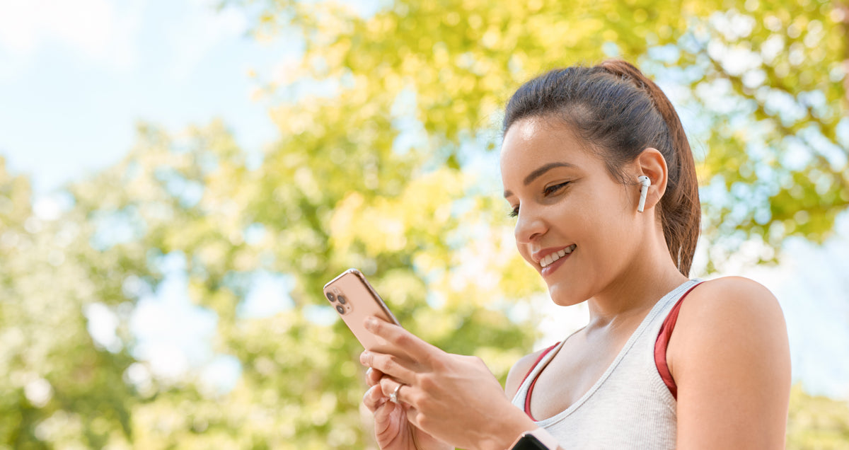 Smiling young woman outdoors looks at smartphone learning about healthy habits for diabetes