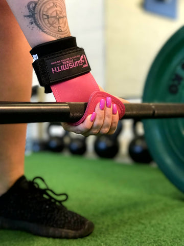 Close-up shot capturing an athlete utilizing the Pink Gunsmith Fitness Power Grips to secure a firm hold on a barbell, showcasing both style and functionality in strength training.