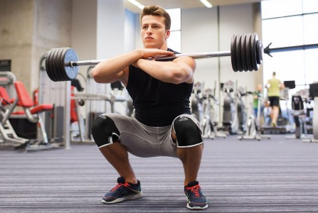 Focused individual demonstrating proper front squat form with a barbell across the shoulders, knees bent, and maintaining a stable core position during the exercise.