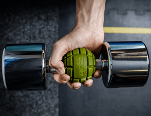 A detailed close-up of an athlete demonstrating the innovative use of Grenadier grips attached to dumbbells, effectively widening the handles to target and enhance grip strength during a workout.