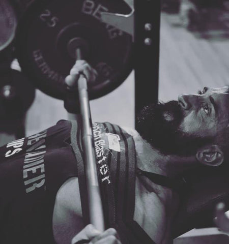 Individual at the gym utilising our Gunsmith Bench Blaster, a supportive training accessory worn around the arms, enhancing stability and form during weightlifting exercises on a bench.
