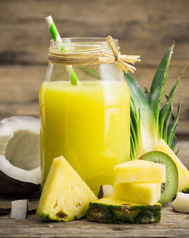 An image of a virgin pineapple coconut cooler beverage that's garnished with a straw and a pineapple wedge
