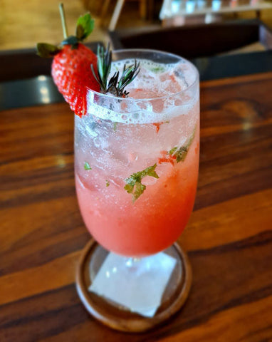 an image of a virgin berry blast mocktail. The drinking glass is garnished with a fresh strawberry.