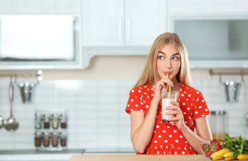 woman drinking protein shake in kitchen