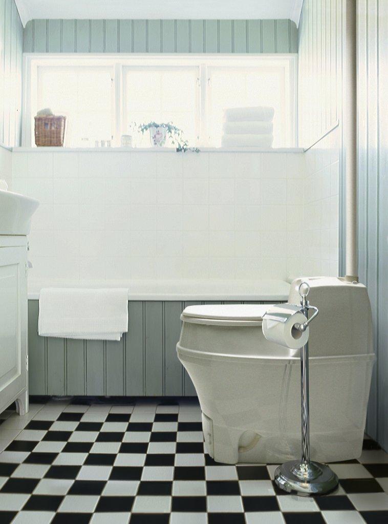 BioLet 15a Composting Toilet in a modern bathroom with black and white checkered floor, green panel walls, and a bright window with assorted decor.