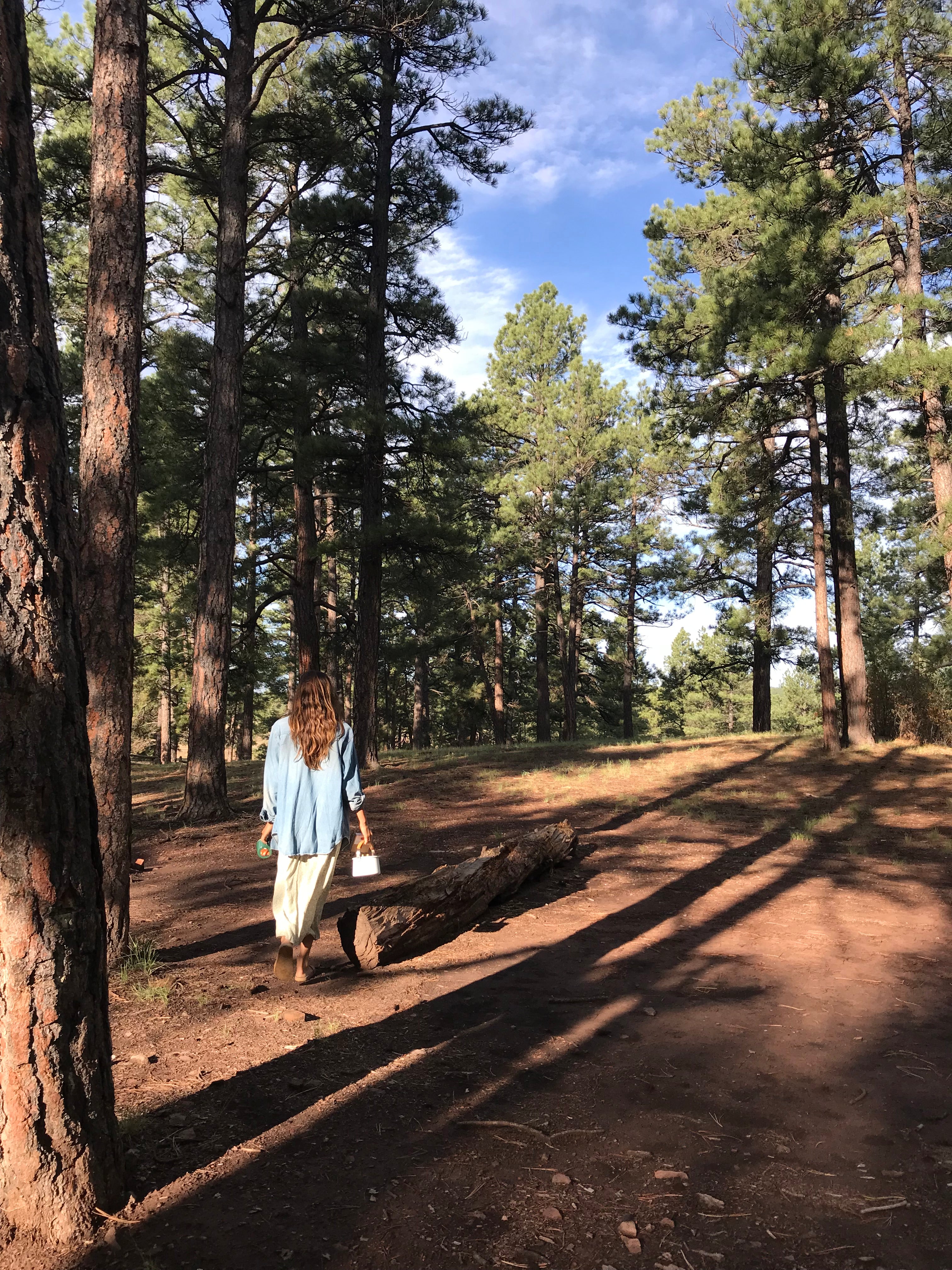 Girl walking with coffee in the forest of California