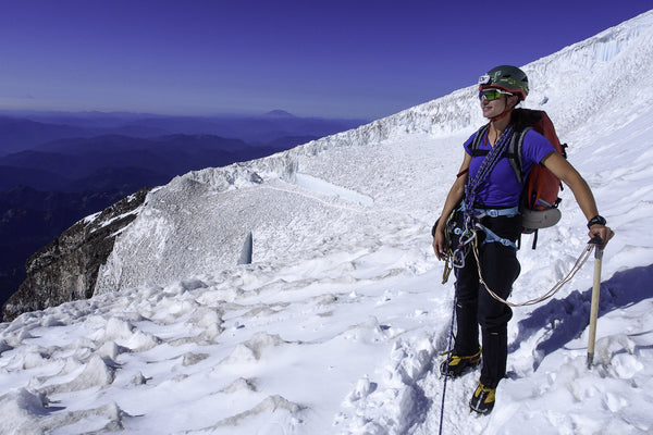 Model standing on snowy mountain carrying hiking equipment
