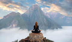 Mädchen saß auf einem Felsen und meditierte in den Bergen