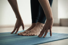 Manos y pies sobre una estera de yoga azul.
